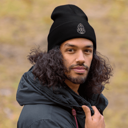 Un bonnet unisexe à revers porté dans un cadre hivernal. Le logo « Le créateur c’est vous » est visible sur le devant, ajoutant une touche d'énergie positive à cette tenue hivernale.